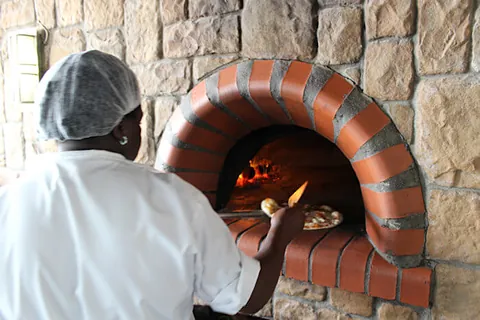 A chef sliding a pizza into the wood-fired oven