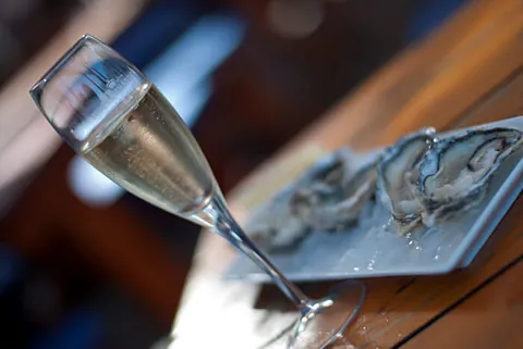 A flute of sparkling wine beside freshly shucked oysters