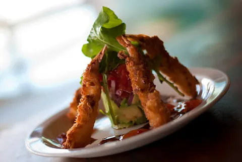 Tempura prawns stacked over a fresh salad
