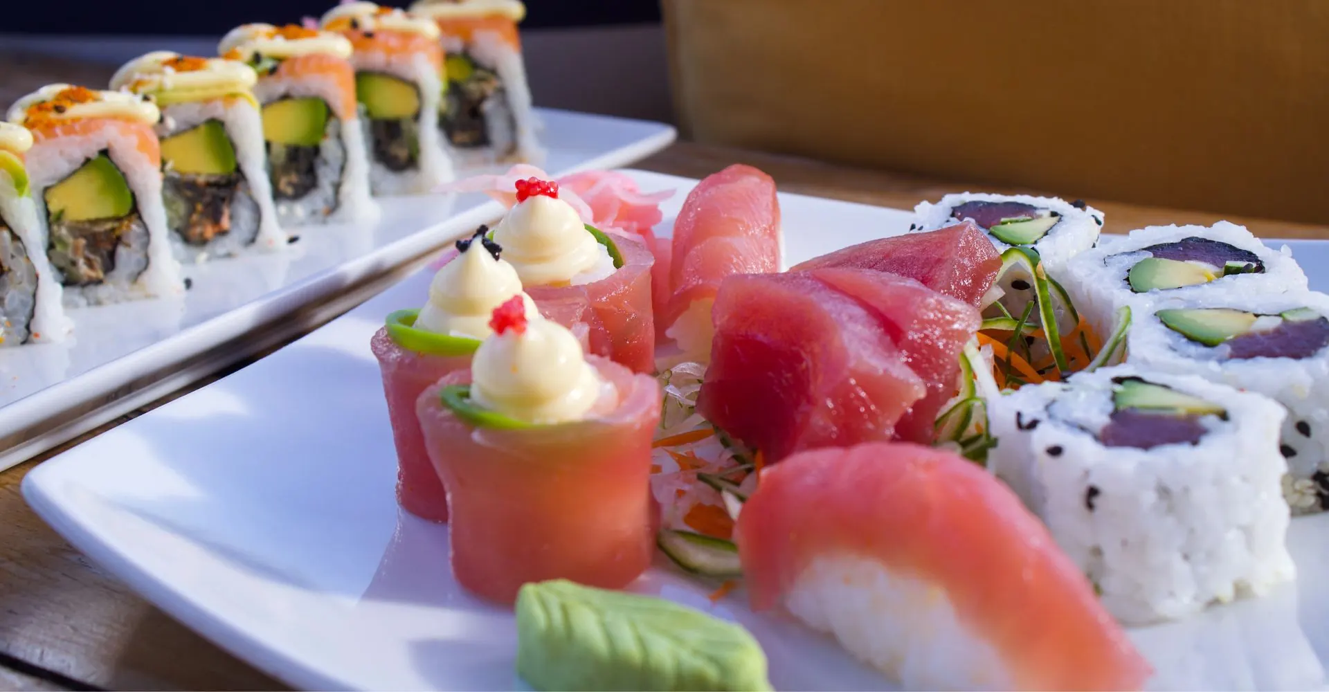 Salmon roses, tuna nigiri and California rolls on white plates